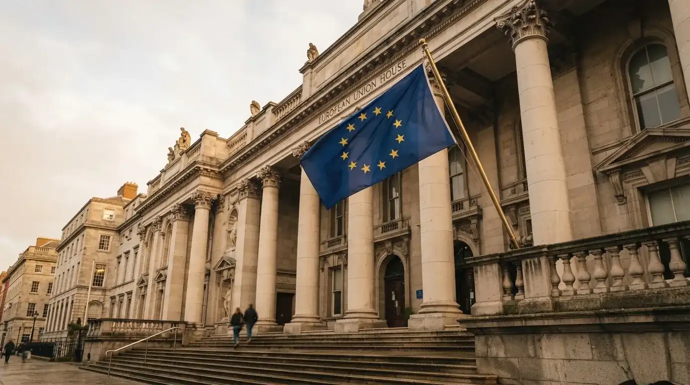 Flaga Unii Europejskiej powiewająca przed budynkiem z kolumnami, zdjęcie z poziomu ulicy.